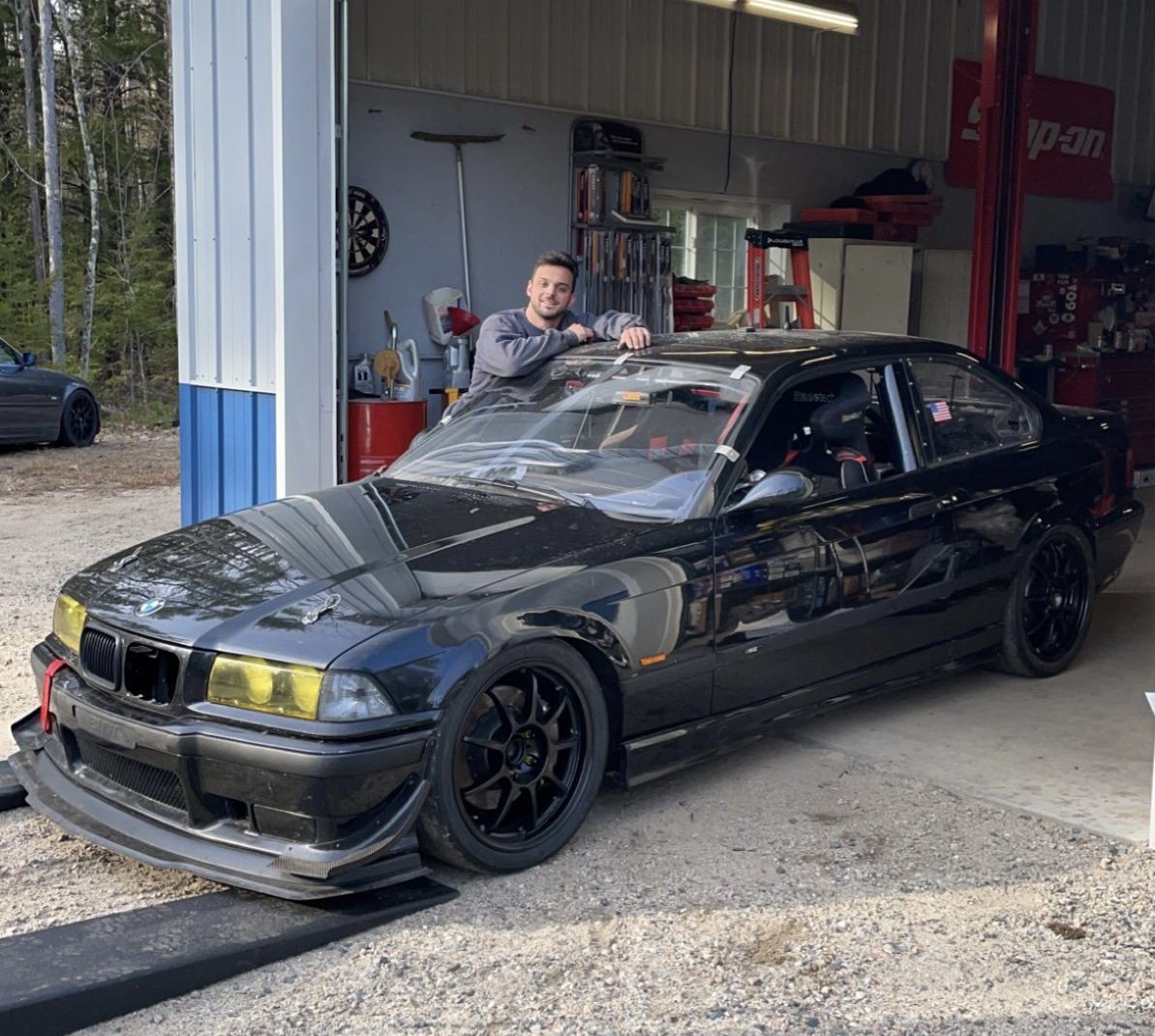 auto repair mechanic standing next to BMW at repair shop in Tuftonboro, NH