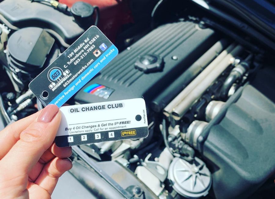 603 motorwerks oil change club card being held over a car engine